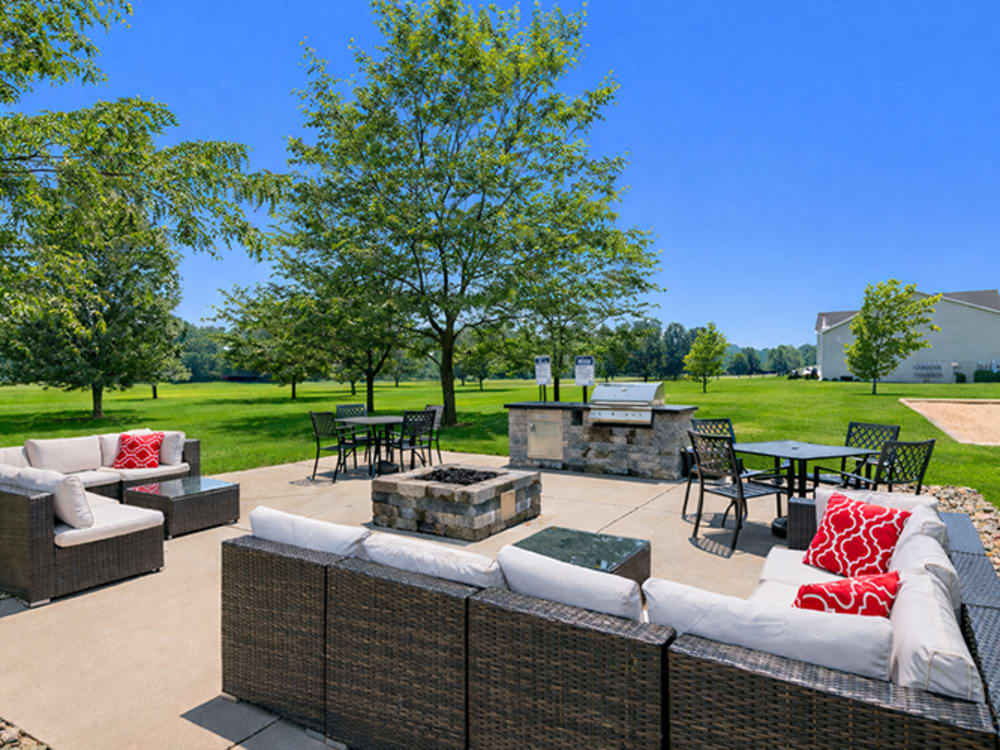 Outdoor lounge area with fire pit and grill station at Somerset Park Apartments in Bath, Michigan