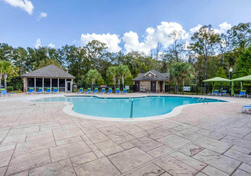 Pool, sundeck with lounge beds covered by canopies near resident clubhouse at Kilnsea Village in Summerville, South Carolina