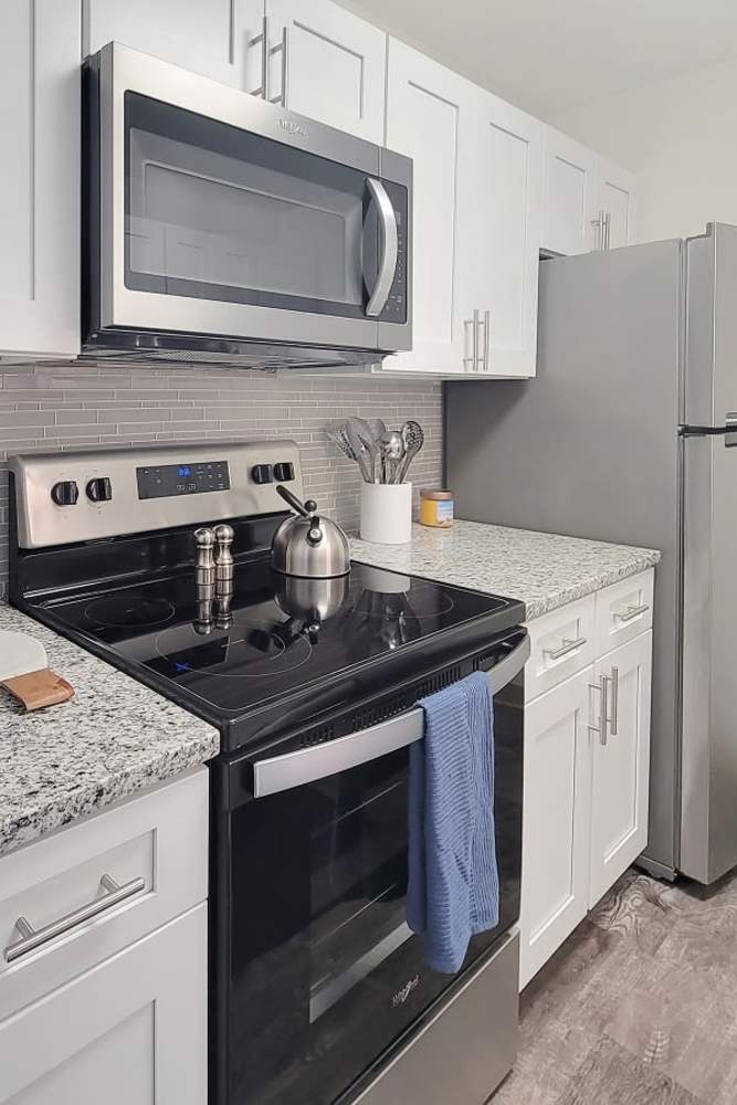 Kitchen with white cabinets, stainless steel appliances, and granite countertops at Squires Manor Apartment Homes in South Park, Pennsylvania