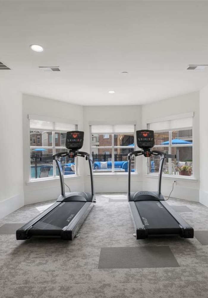 Treadmills facing windows with a view of the community pool in the fitness center at Chace Lake Villas in Birmingham, Alabama