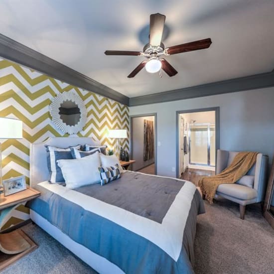Bed and oversized chair in a model home's bedroom at Waterstone at Cinco Ranch in Katy, Texas