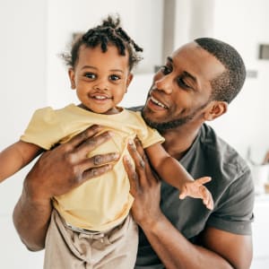 Happy father holding smiling toddler at Highlands of Duncanville in Duncanville, Texas