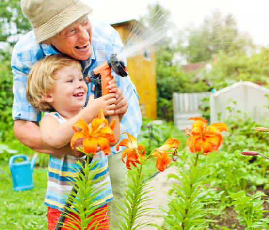 Resident and grandson watering flowers at The Phoenix at Johnson Ferry in Marietta, GA