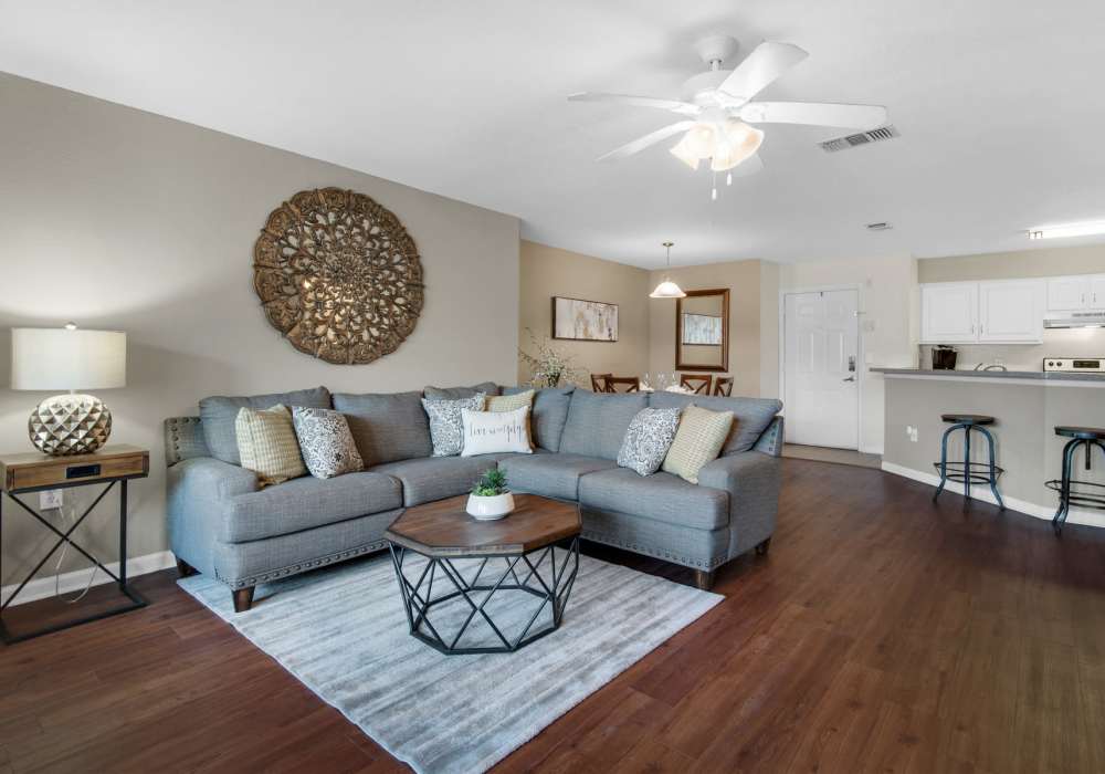 Modern living room with large couch, ceiling fan and wood-style flooring at Reserve at Northshore in Lynn Haven, Florida