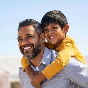 Resident father giving his son a piggyback ride outside their new home at Riverbend in Arlington, Texas