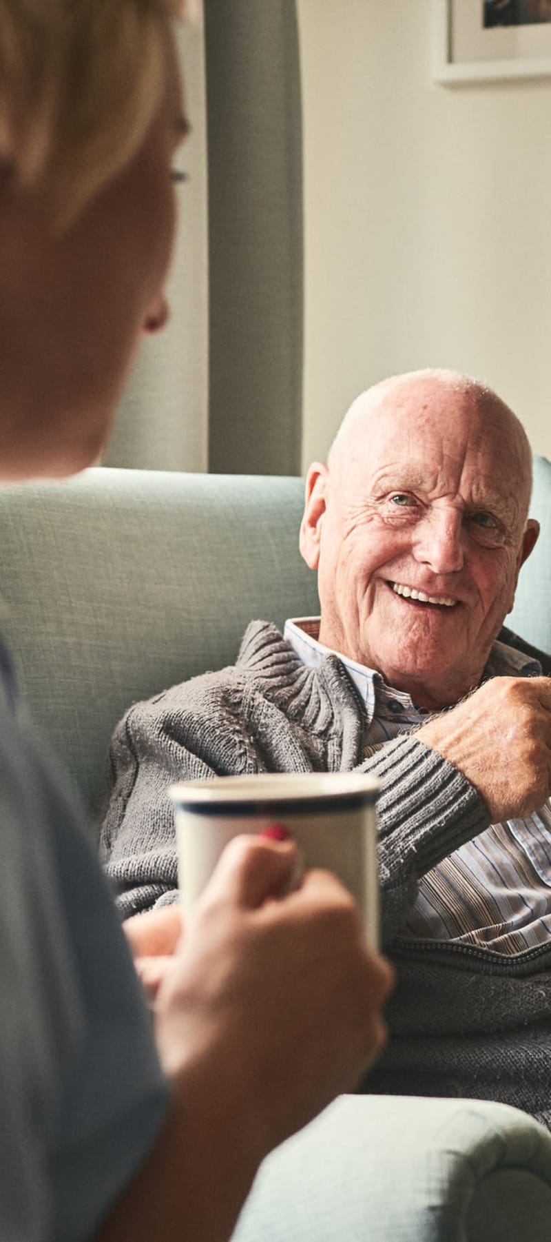 Two resident sitting and talking over coffee in a common area at a WISH community