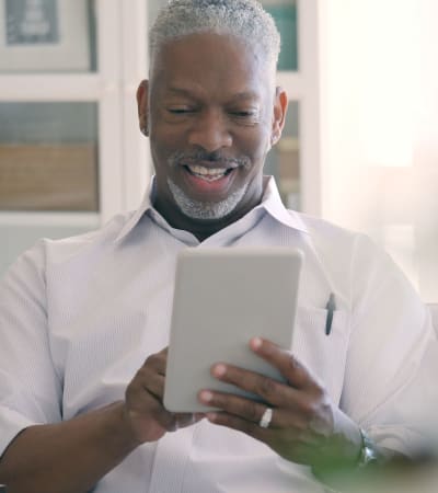 Older gentleman searching the internet on his tablet at Fairbrooke Senior Apartments in Aberdeen, Maryland