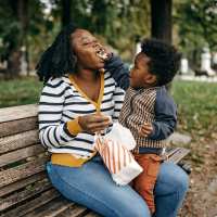 Woman and child sharing snacks on a park bench at Bellwood Gateway Apartments in Bellwood, Illinois