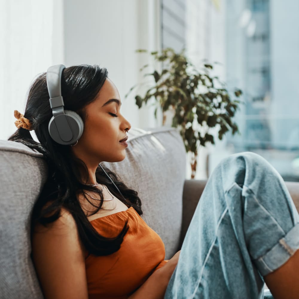 Resident relaxing on her couch with headphones on in her new home at Ellington Midtown in Atlanta, Georgia