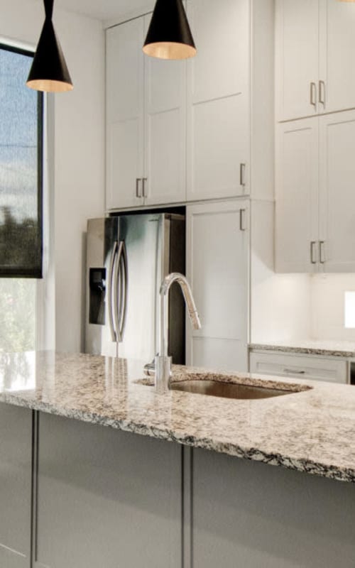 Modern kitchen with granite counter tops and stainless steel fridge at The Collection Townhomes in Dallas, Texas