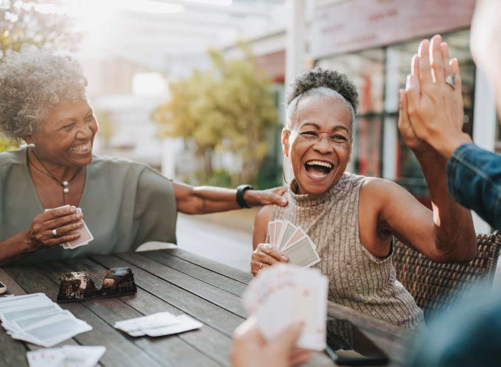 Senior friends playing cards and high-fiving at Novelle in San Jose, California