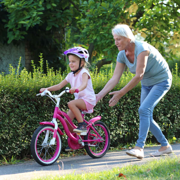 Resident helping her grandchild learn to ride a bicycle at Pacifica Senior Living Heritage Hills in Hendersonville, North Carolina