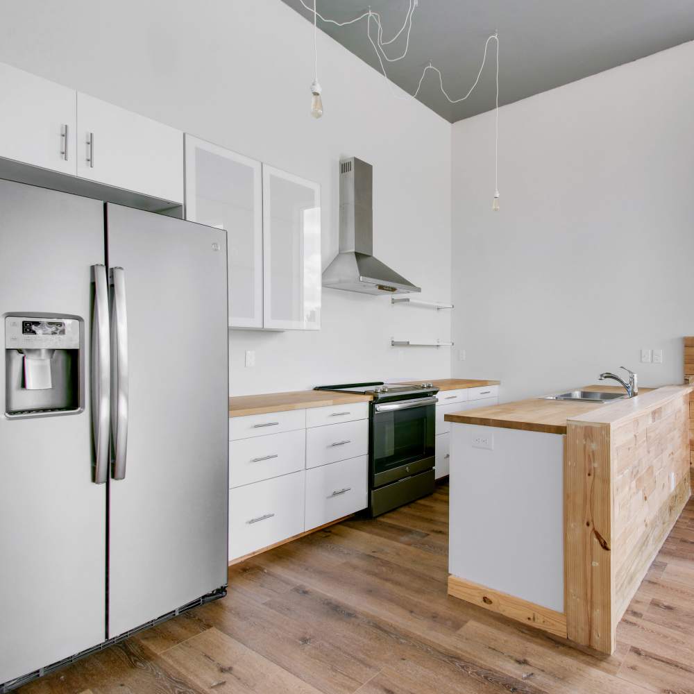 Kitchen with large stainless-steel refrigerator and hood at The Lofts at 305 in Bryan, Texas