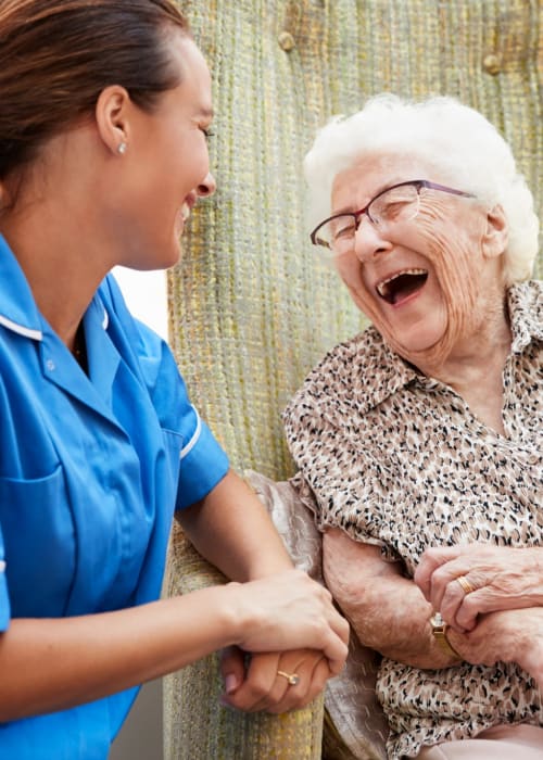 Senior woman and staff member laughing together at The Pillars of Hermantown in Hermantown, Minnesota