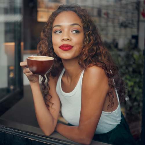 Woman enjoying coffee by window at Jefferson Manor Townhomes in Fairport, New York