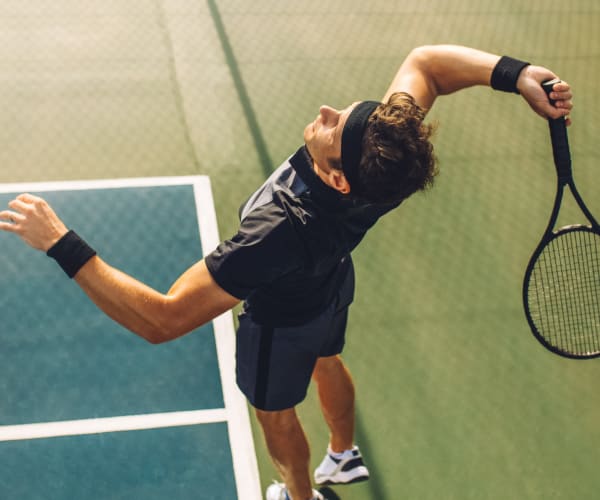 Resident mid-serve on the tennis court at a Graham Residential community in Miami Lakes, Florida