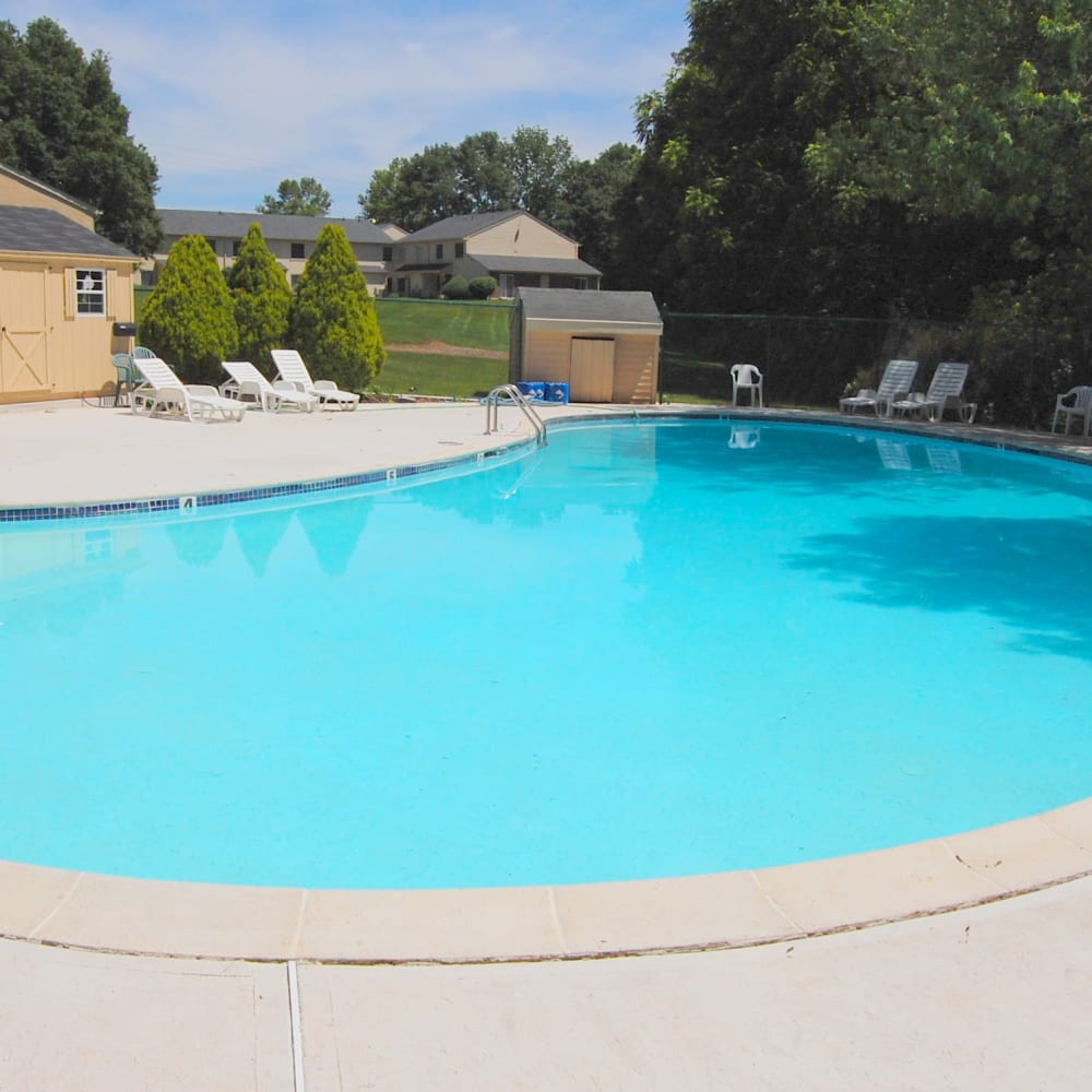 Swimming pool surrounded by lounge chairs at Montgomery Woods Townhomes in Harleysville, Pennsylvania