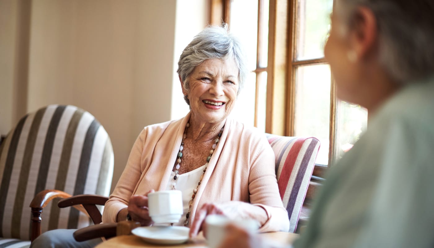 Two happy residents smiling and chatting over coffee at The Pillars of Prospect Park in Minneapolis, Minnesota