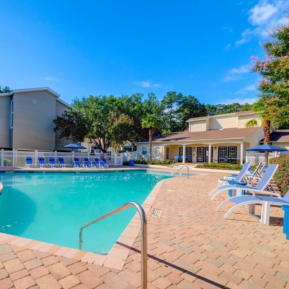 Swimming pool surrounded by lounge chairs and flowering trees at Park at Northside Apartments & Townhomes in Macon, Georgia