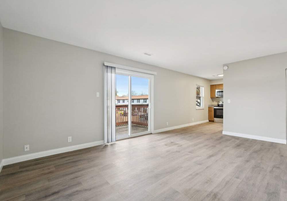 Living room with access modern kitchen and private balcony at Charleston Square Apartments in Columbus, Indiana