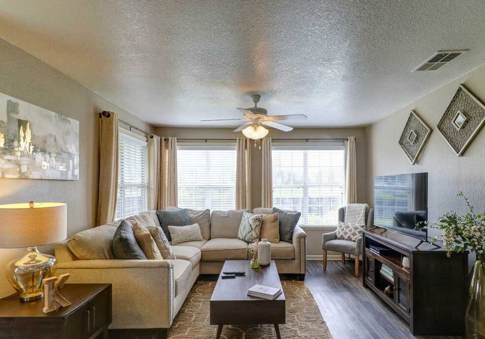 Living room with large couch, chair, coffee table, large window and flat screen television at The Reserve at Kanapaha in Gainesville, Florida