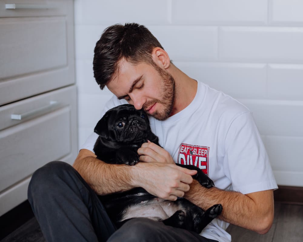 Resident hugging his dog in the kitchen of his new home at Olympus at the Canyons in Herriman, Utah