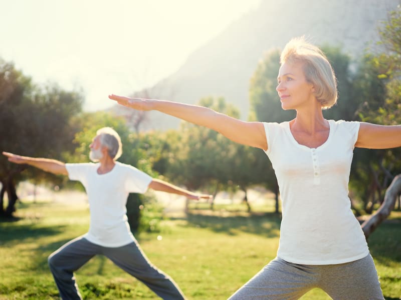 Two residents doing yoga outside on a sunny day at MBK Senior Living in Irvine, California