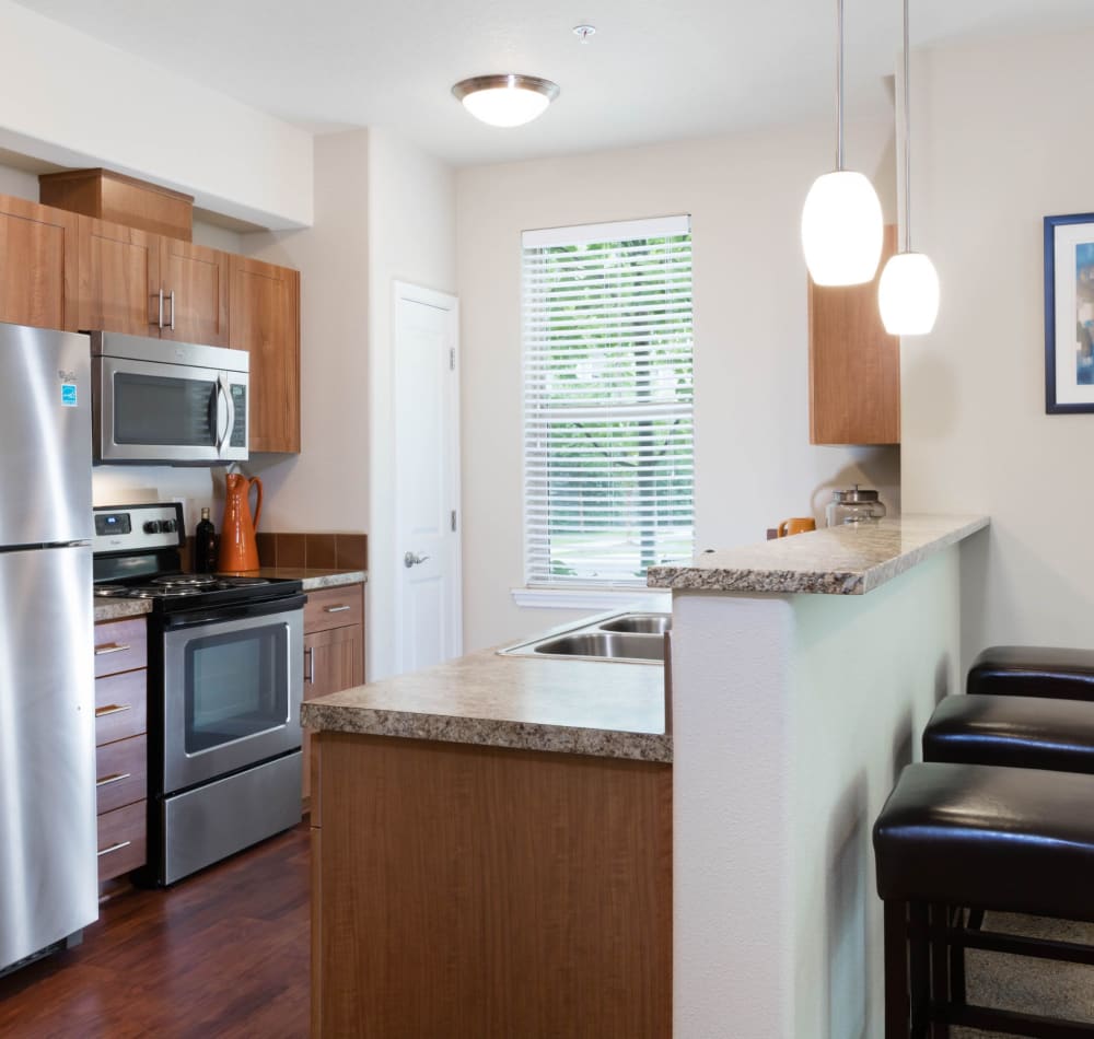 Modern kitchen with granite countertops with counter seating at The Jones in Hillsboro, Oregon