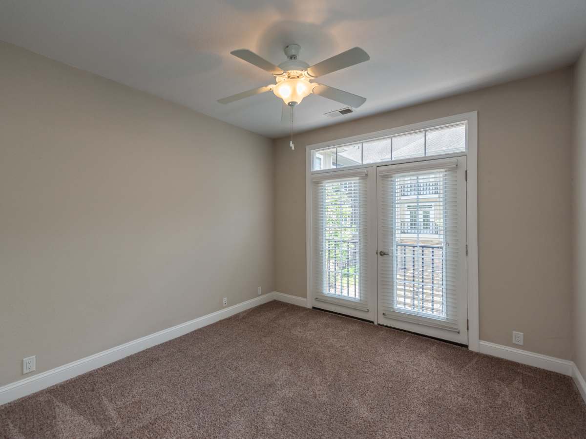Bedroom with Carpeted Flooring, Ceiling Fan with Lighting, and Glass Doors with Blinds Leading to the Balcony at Red Knot at Edinburgh in Chesapeake, Virginia