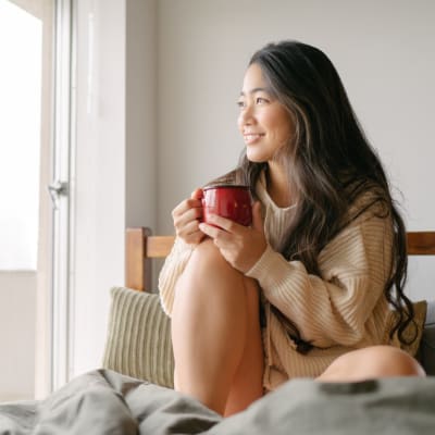 A resident with a hot beverage in bed at Adobe Flats II in Twentynine Palms, California