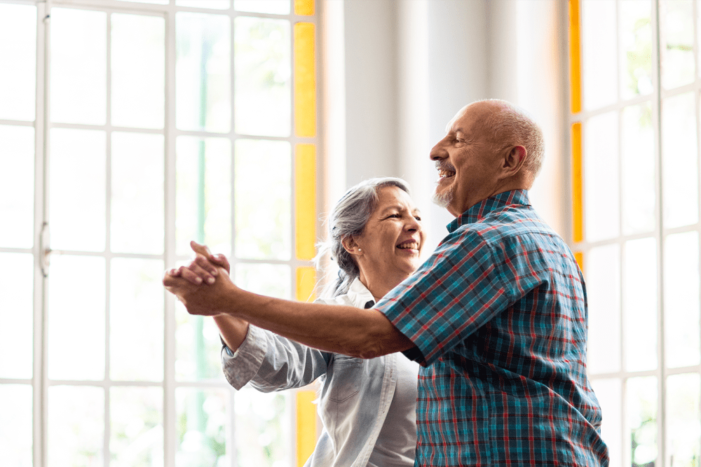 Two residents dancing in a brightly lit lounge at Hanover Place in Tinley Park, Illinois