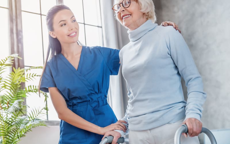 Caregiver helping a resident with a walker rise to her feet at Blossom Ridge in Oakland Charter Township, Michigan