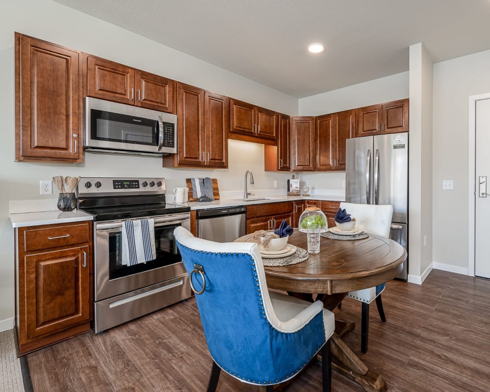 Apartment kitchen with hardwood floors, wooden cabinets, and stainless steel appliances at The Pillars of Hermantown in Hermantown, Minnesota