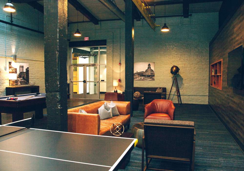 Clubhouse lounge with leather sofa, pendant lighting and industrial style decor at City View Lofts in Richmond, Virginia