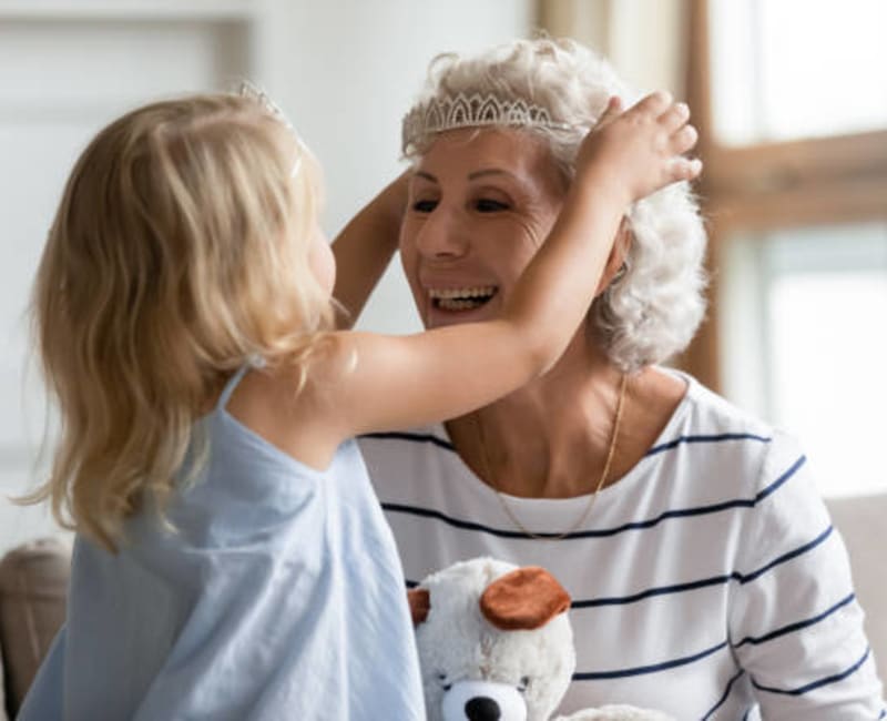 A child placing a tiara on a resident's head at Towerlight in St. Louis Park, Minnesota