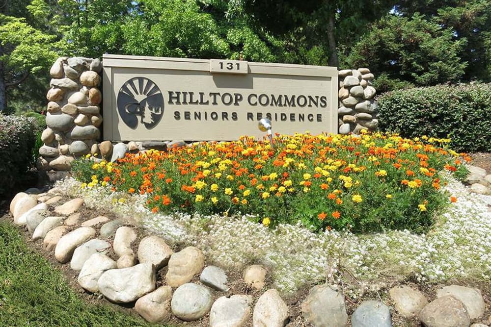 Exterior sign with flowers surrounding at Hilltop Commons Senior Living in Grass Valley, California