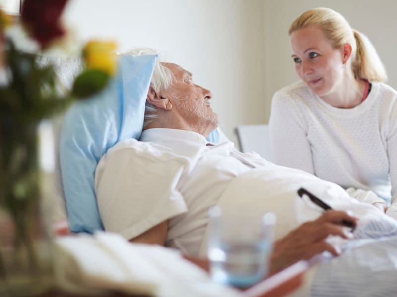 Caretaker sitting and conversing with a resident in hospice care at Fair Oaks Health Care Center in Crystal Lake, Illinois