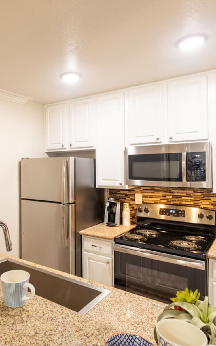 Modern kitchen with sleek, stainless-steel appliances in a model home at Haven Warner Center in Canoga Park, California