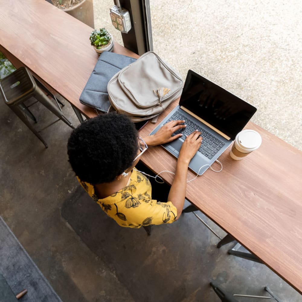 Resident getting some work done on her laptop from a café near Oaks Trinity in Dallas, Texas