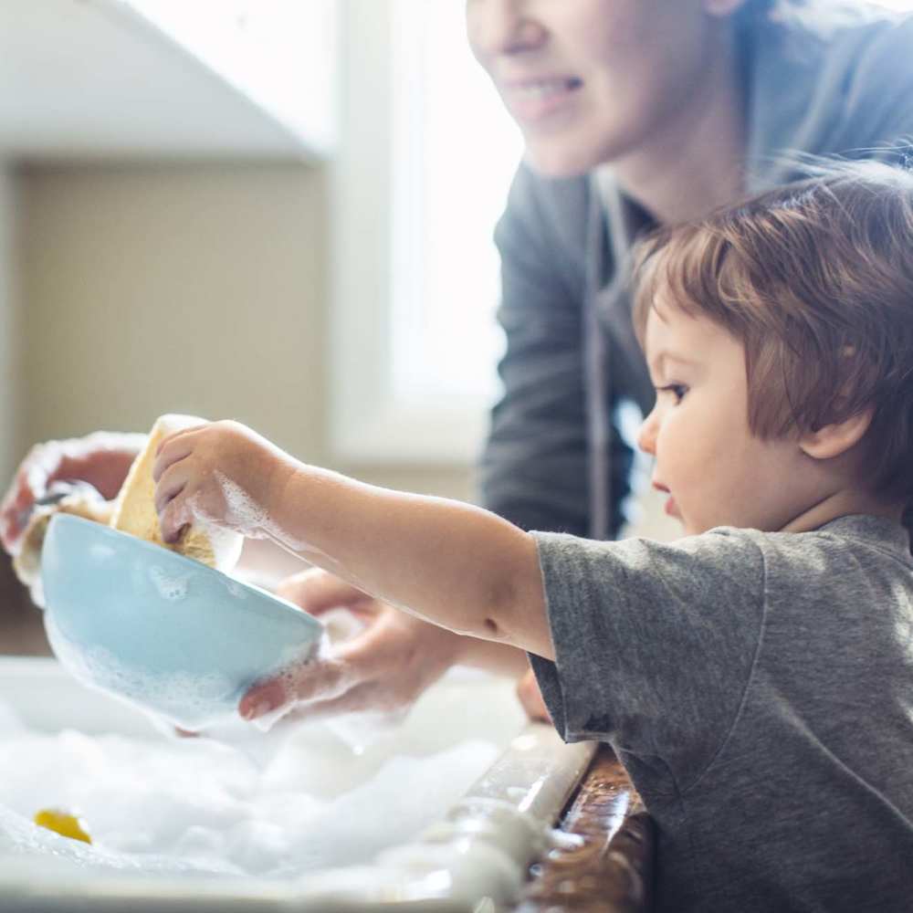 A child and his parent washing the dishes together at Pecan Bend in Mansfield, Texas