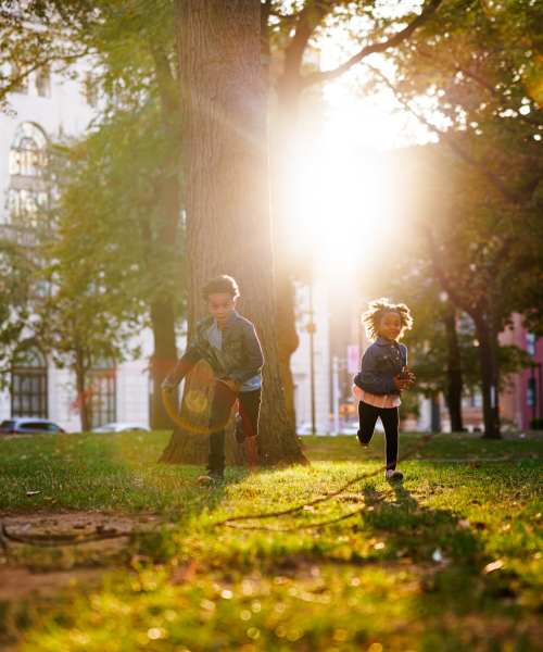 Kids enjoying a sunny outdoor lawn with greenery and walking paths at Granada Gardens Apartments in Warrensville Heights, Ohio