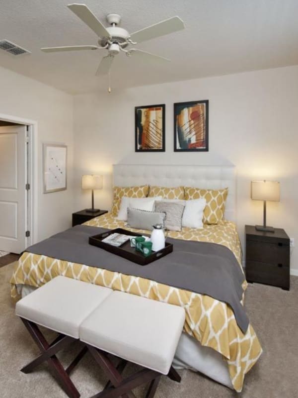 Model bedroom with a ceiling fan and walk-in closet at Evander Square in Celebration, Florida