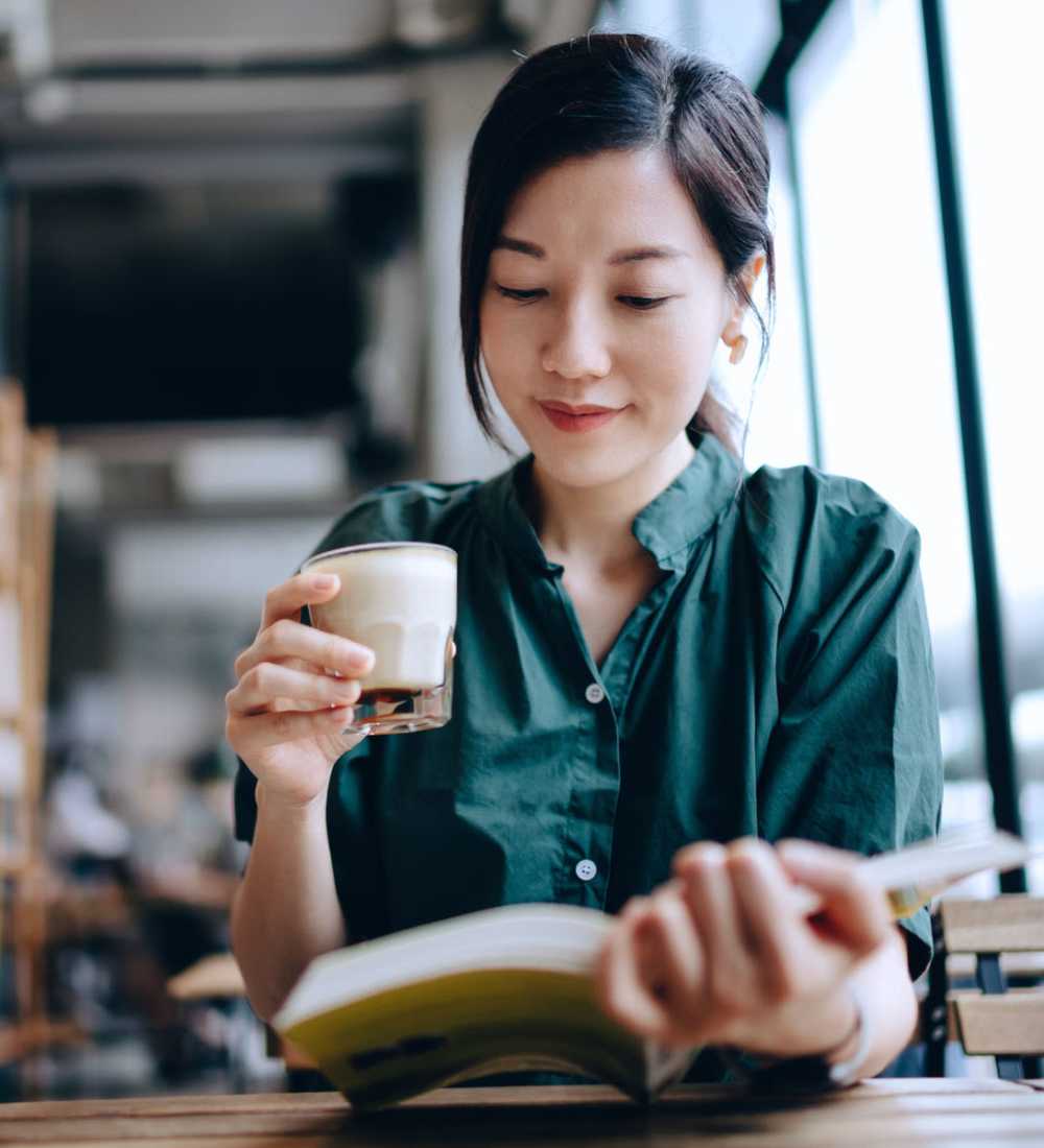 Student reading a book and having coffee at a university near The Lorimer in Denton, Texas