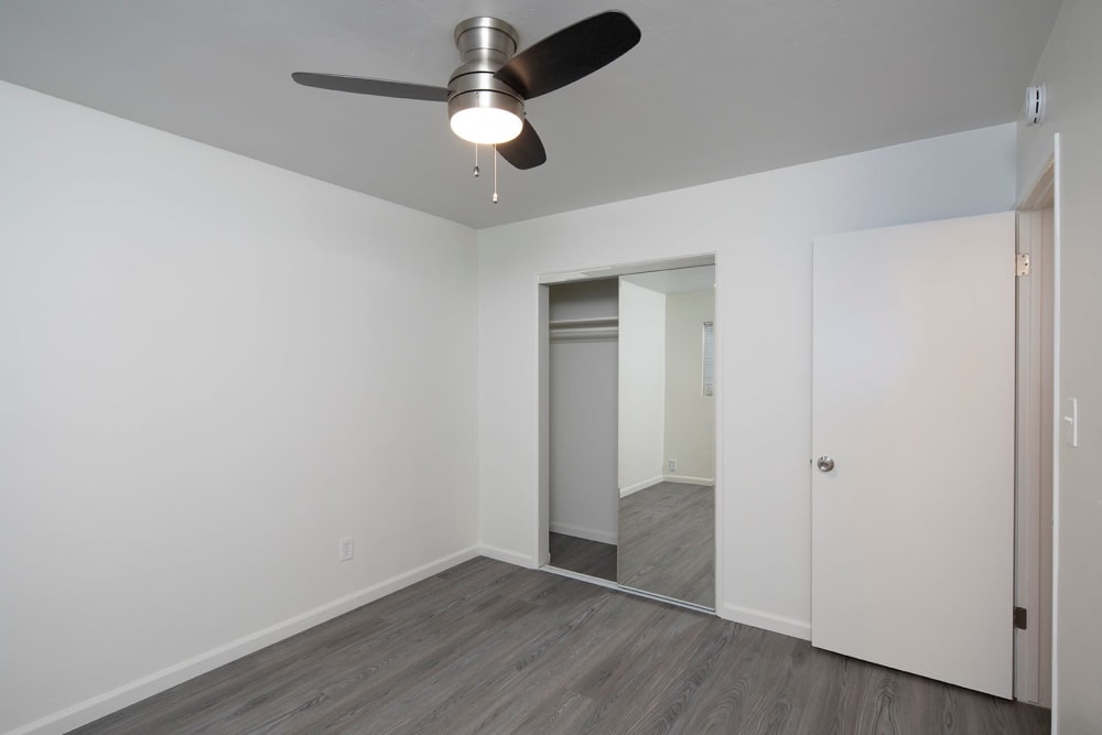 Bedroom space with upgraded flooring and mirrored closets at Ocean Palms Apartments in San Diego, California