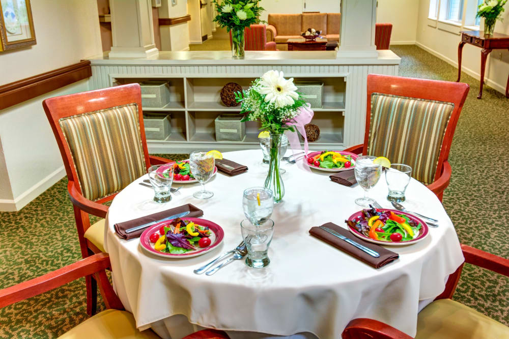 Dining room table set with fresh garden salads at Timberwood Court Memory Care in Albany, Oregon