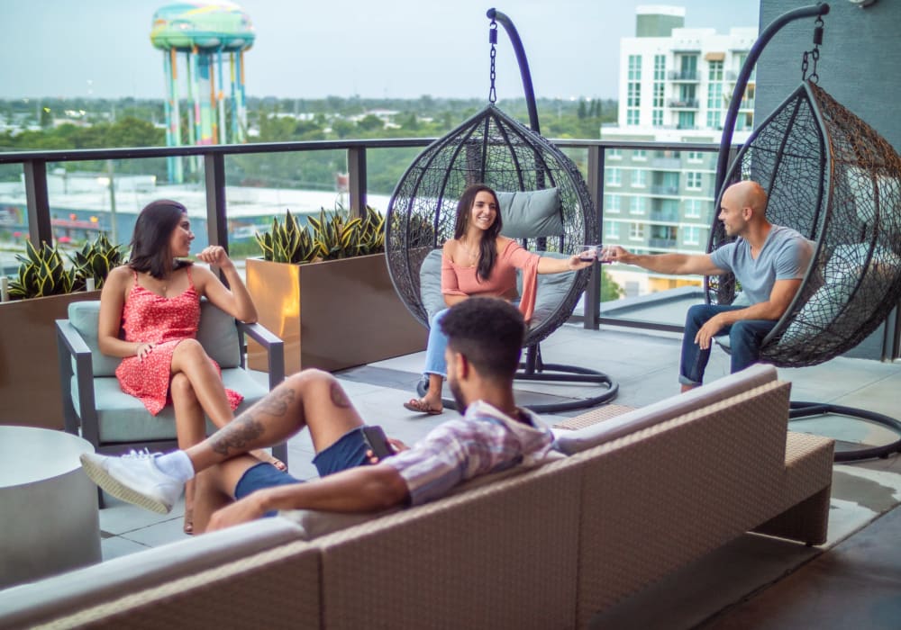 Residents enjoying the rooftop deck with hanging chairs at Motif in Fort Lauderdale, Florida