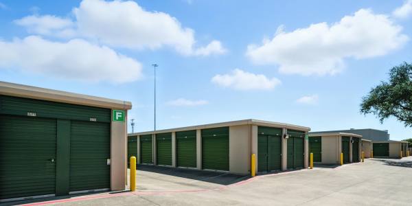 A row of storage units with green gates at Storage Hub - Redland in San Antonio, Texas
