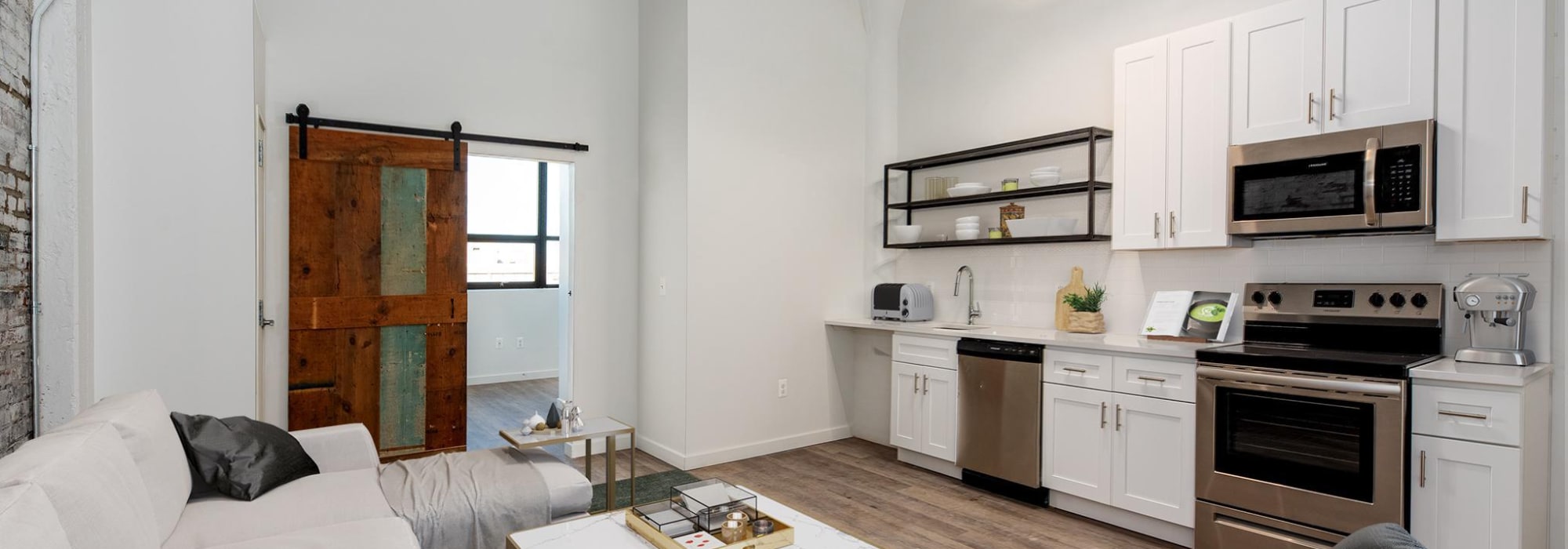 Living room and kitchen with sliding wooden door at Brush Factory Lofts in Philadelphia, Pennsylvania