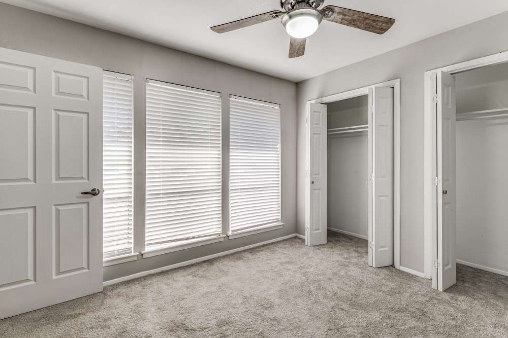 Unfurnished bedroom with large windows, ceiling fan and closet at Tribecca Pointe Apartments in Hurst, Texas