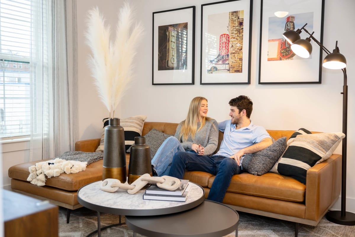 Couple relaxing on a leather sofa in their living room at The Scottie in Nashville, Tennessee